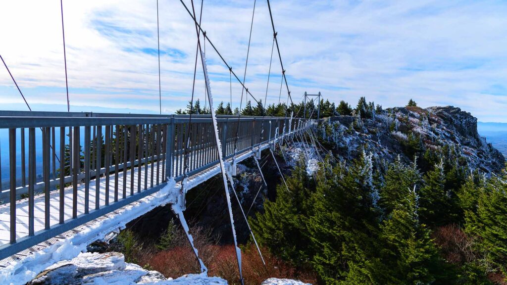 A snow-dusted suspension bridge stretching over a dramatic mountain ridge with panoramic views—an exhilarating hidden US destination in North Carolina.