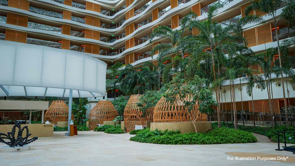 Spacious indoor area with modern architecture, tropical plants, and wooden seating structures — design elements often found in eco-friendly hotels.