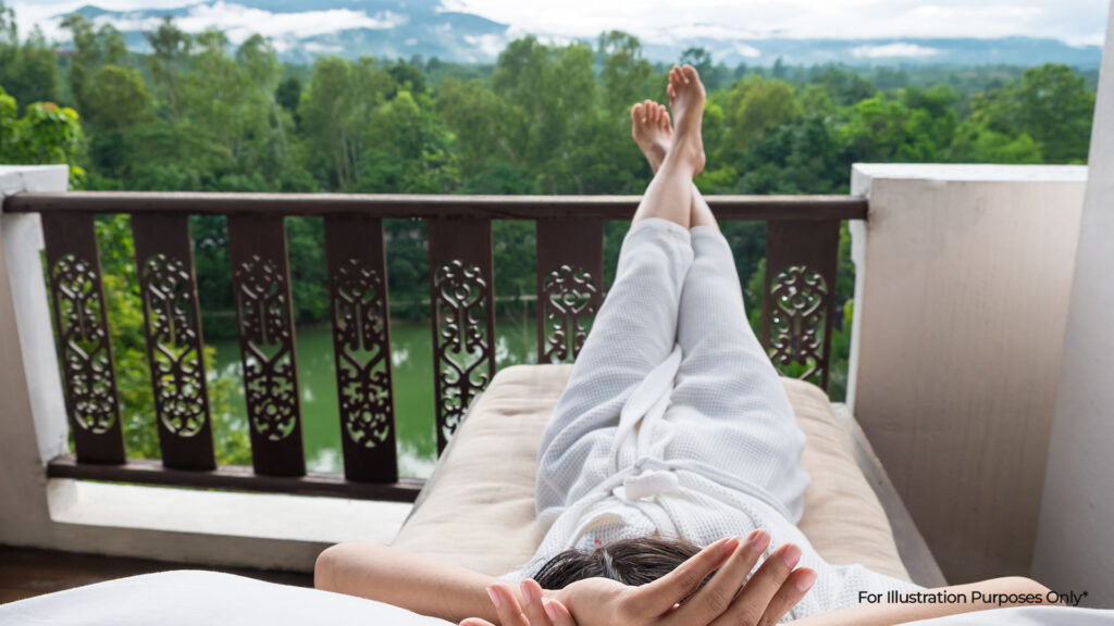 Guest relaxing on a balcony with lush greenery and river views — a tranquil experience often sought at eco-friendly hotels.