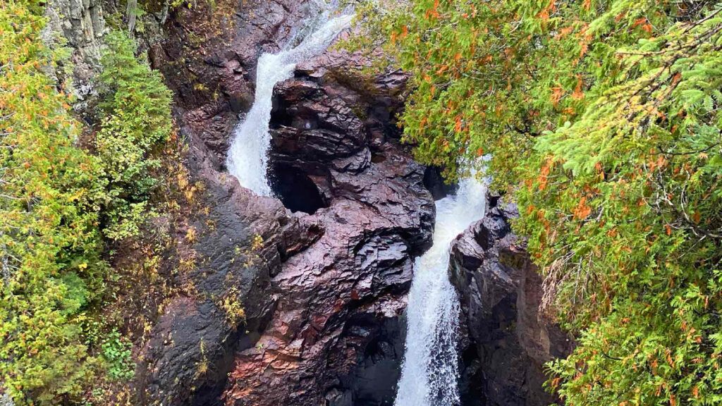 Aerial view of Devil’s Kettle waterfall in Minnesota, a mysterious and hidden US destination surrounded by lush greenery.