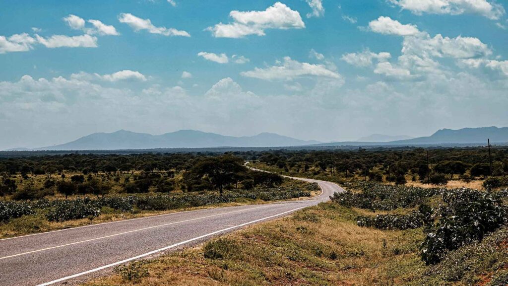 A scenic stretch of the High Road to Taos winds through open desert terrain with distant mountains under a wide blue sky, showcasing one of the most iconic road trips in USA.