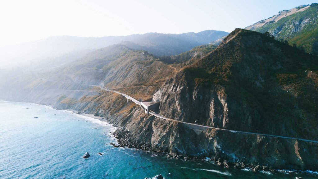 A breathtaking view of California’s Pacific Coast Highway winding along dramatic cliffs above the ocean, perfect for unforgettable road trips in USA.