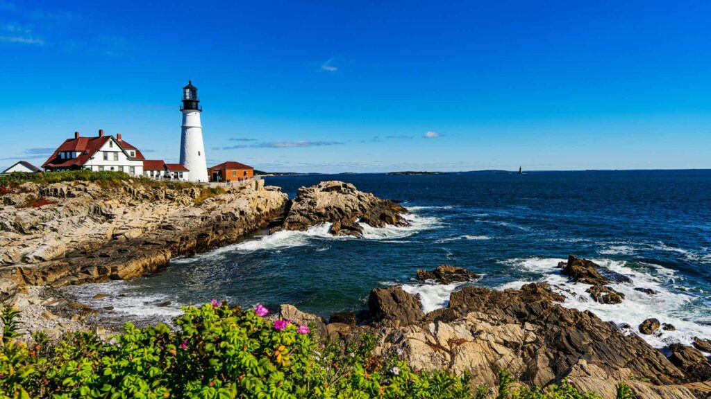 Scenic view of the historic Portland Head Light on the rocky coast of Maine, offering a perfect setting for affordable family vacations with coastal charm and outdoor adventure.