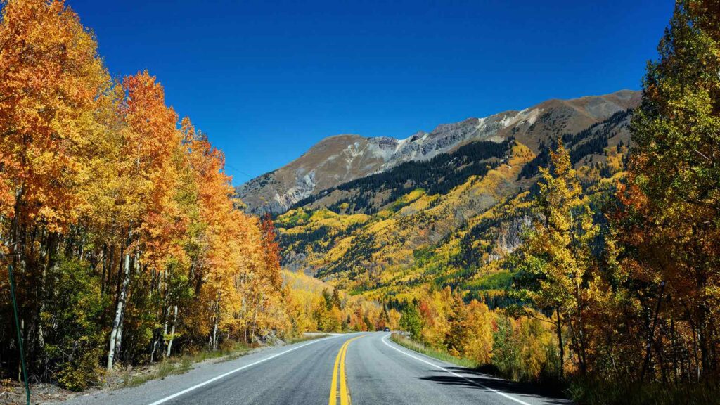 Vibrant autumn colors line the scenic San Juan Skyway in Colorado, with winding roads and mountain views, showcasing one of the most picturesque road trips in USA.
