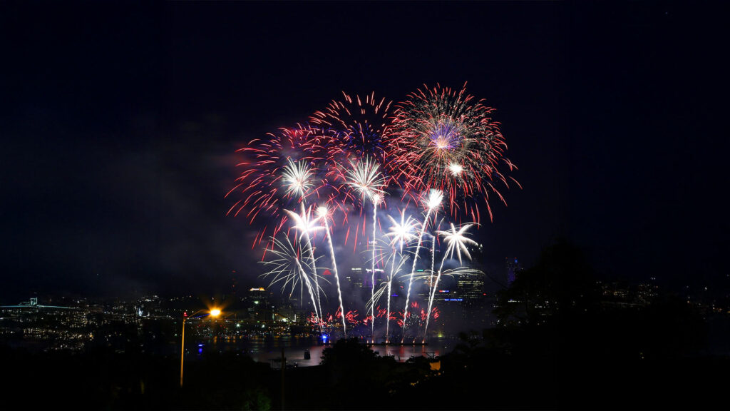 Colorful fireworks lighting up the night sky over a city skyline to celebrate America's Independence Day on the 4th of July.