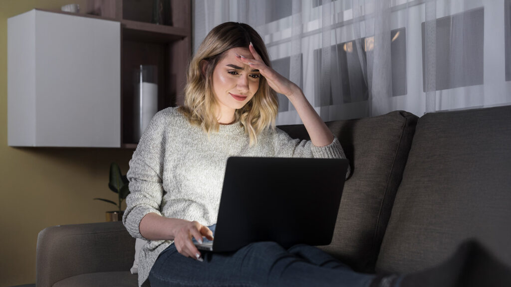 Concerned woman using her laptop late at night, realizing she made a booking mistake due to lack of research