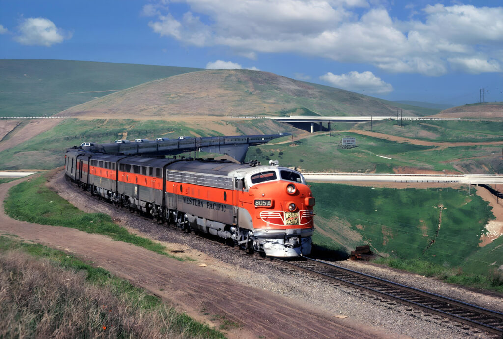 Western Pacific California Zephyr train with orange and silver livery traveling through green hills under a blue sky.