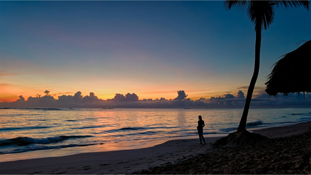 Silhouette of a person walking along the beach at sunset near Punta Cana all inclusive resorts