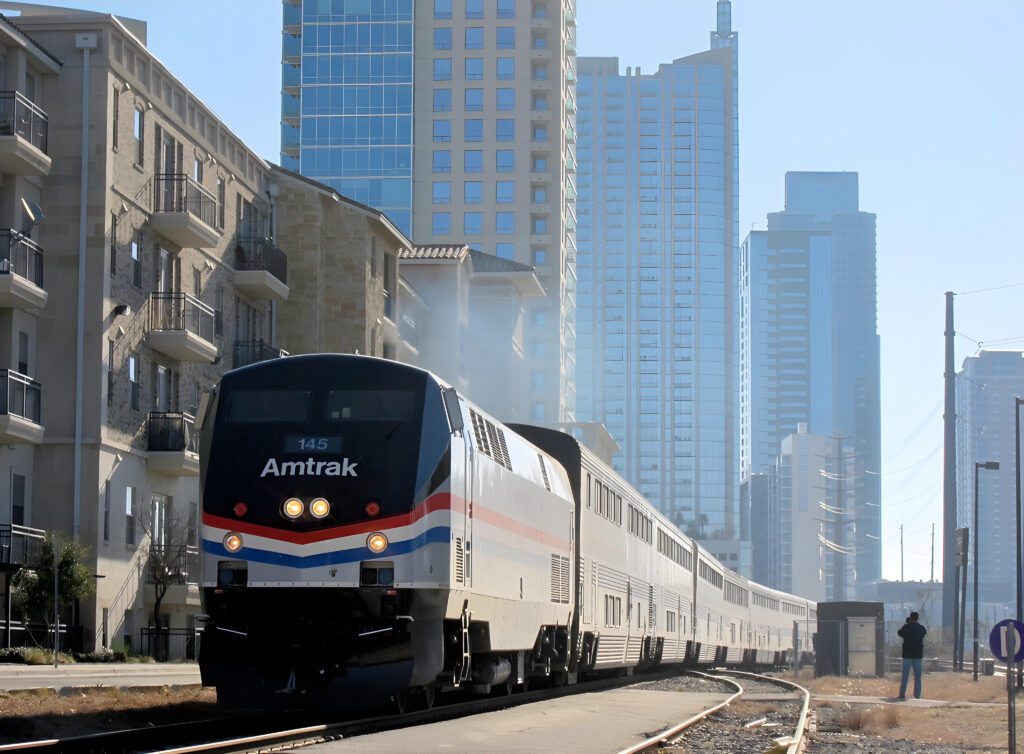 Amtrak Texas Eagle train passing through a modern cityscape with high-rise buildings in the background.