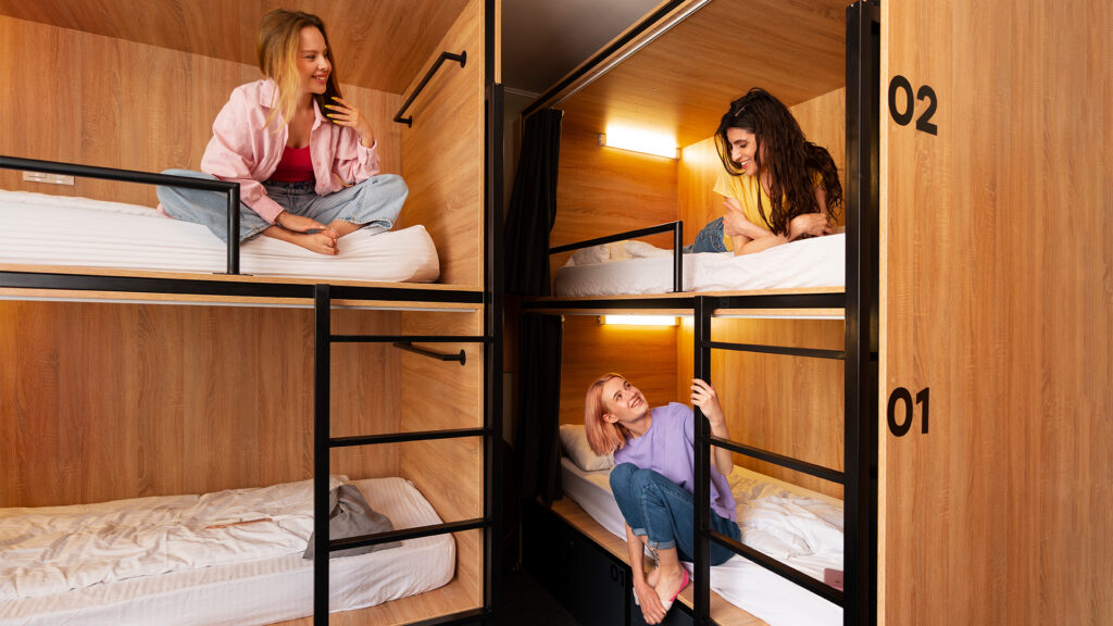 Modern hostel bunk beds with young travelers enjoying their stay – a great option for cheap stays in USA.