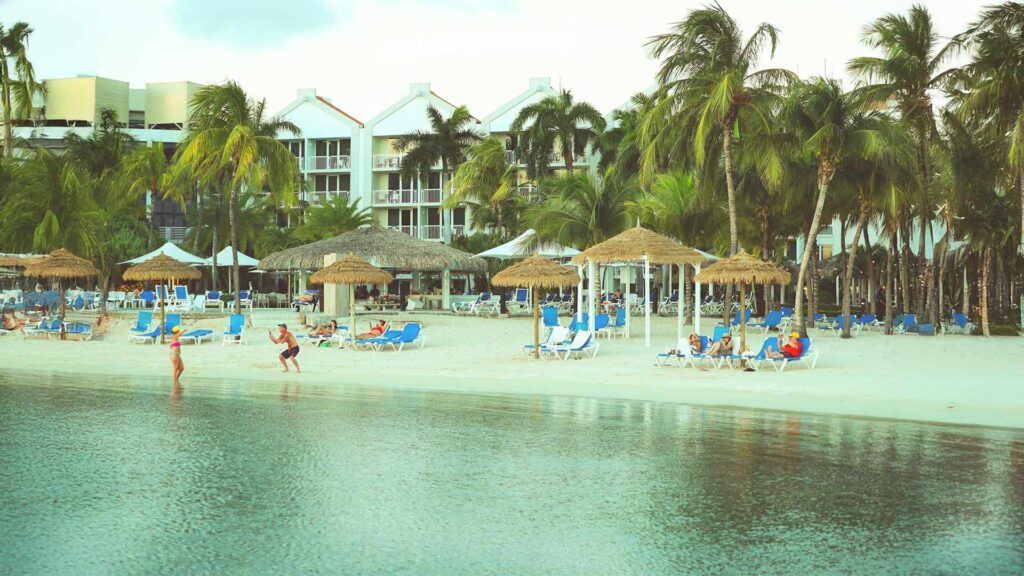 Beachfront hotels in the Caribbean Islands with sun loungers and palm trees