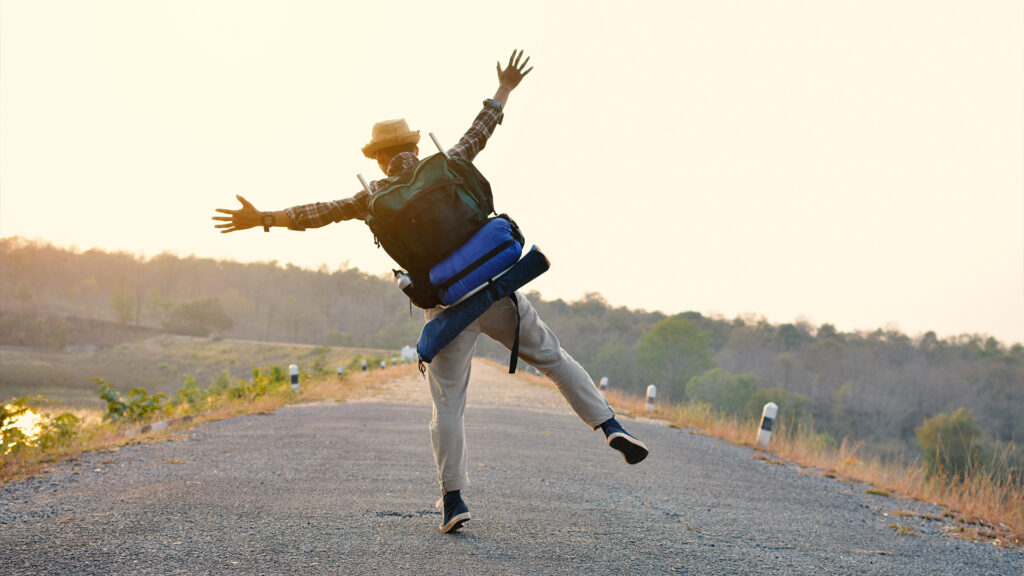 A solo traveler jumps on an open road, embracing the adventure and excitement of a vacation.