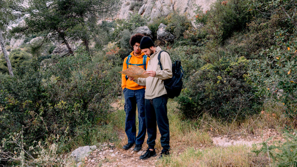 Two hikers examining a map while standing in a forest, preparing for their next adventure.