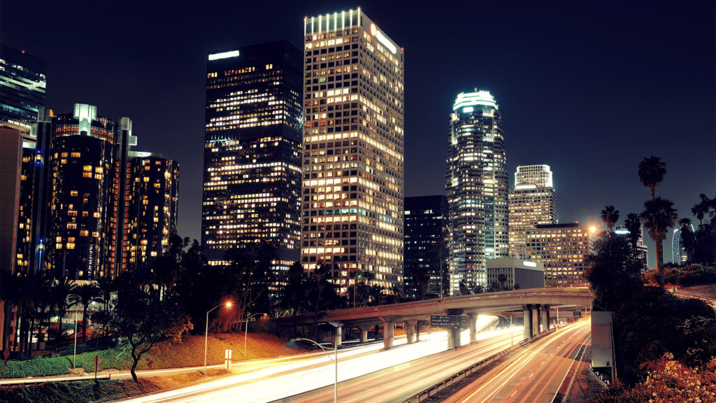 A scenic night view of Los Angeles downtown with illuminated skyscrapers and a bustling highway. Choose from the best Los Angeles hotels for a perfect city stay.