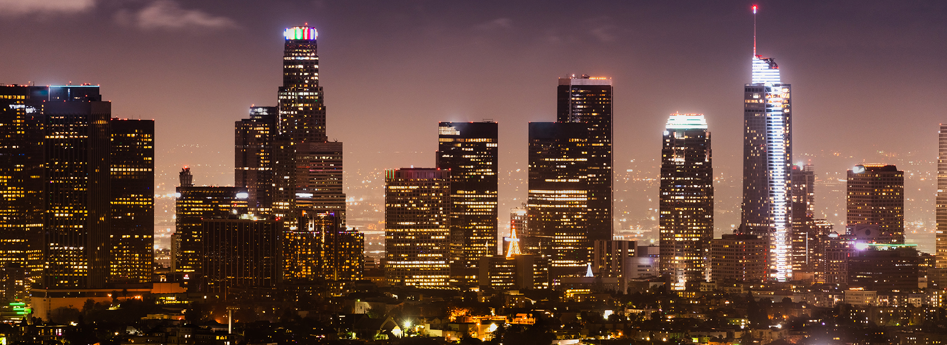 Los Angeles city skyline illuminated at night with modern high-rise buildings and bright lights. Explore nearby Los Angeles hotels to stay close to the city’s vibrant nightlife.