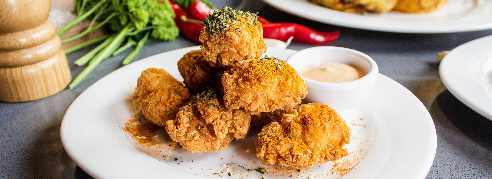 Crispy fried rocky mountain oysters served with dipping sauce, garnished with herbs and spices.