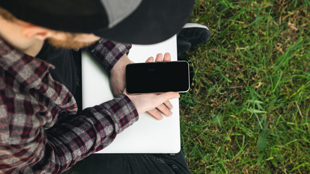 Traveler using a smartphone outdoors while working remotely in nature – Sustainable Travel Tips for eco-friendly digital nomads.