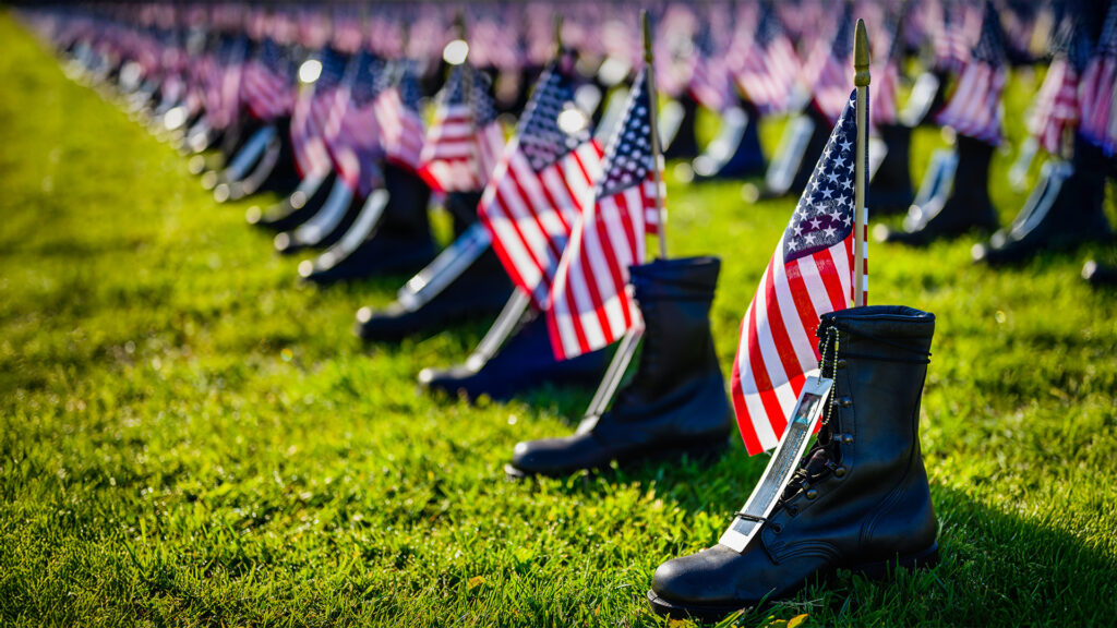 Boots with American flags placed on them at a memorial site, honoring veterans who made the ultimate sacrifice on Veterans Day.