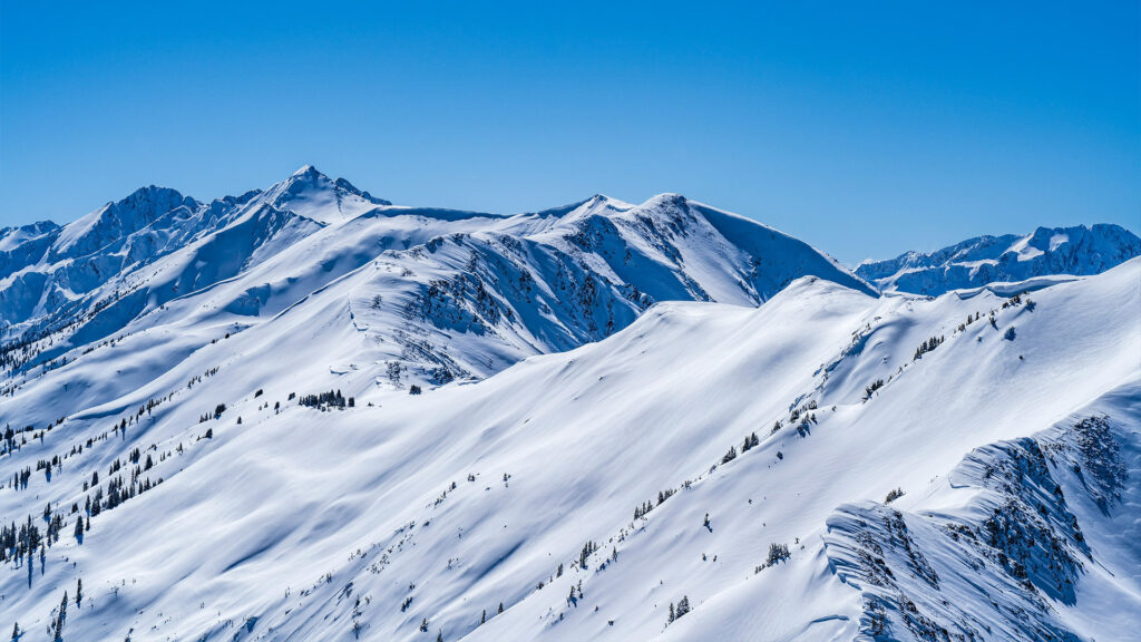 The pristine snow-covered peaks in a mountainous region, offering breathtaking views and outdoor activities for winter travel. A must-see among the best places to visit in December in the US.