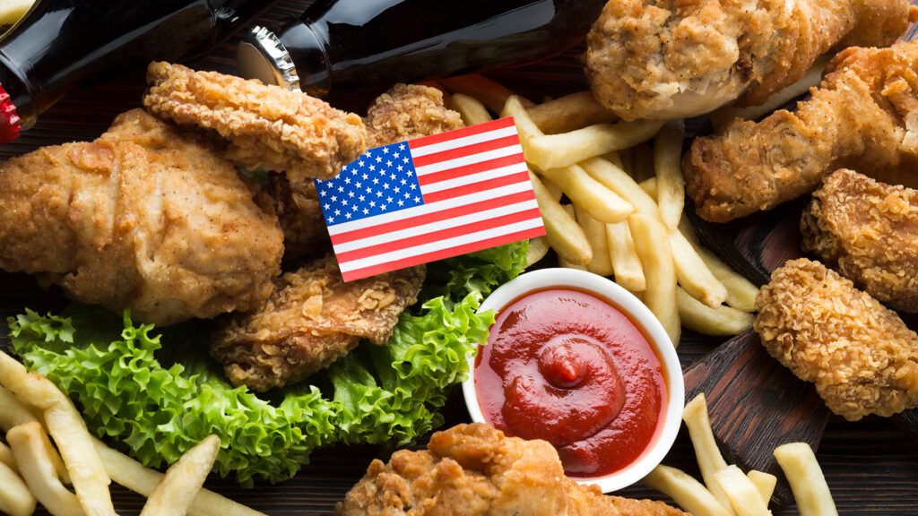 A plate of fried chicken, fries, and a soda with an American flag on top, a fitting treat to enjoy on Veterans Day.