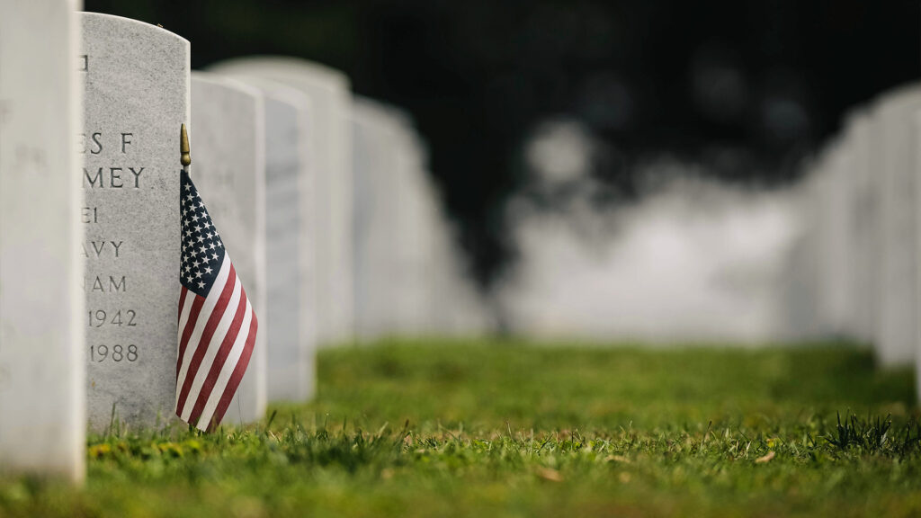 An American flag placed on a veteran’s grave, reflecting the respect and remembrance of those who served on Veterans Day.