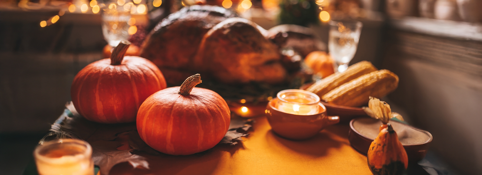 Warm Thanksgiving table with pumpkins, candles, and traditional dishes, setting the mood for cozy Thanksgiving getaways.