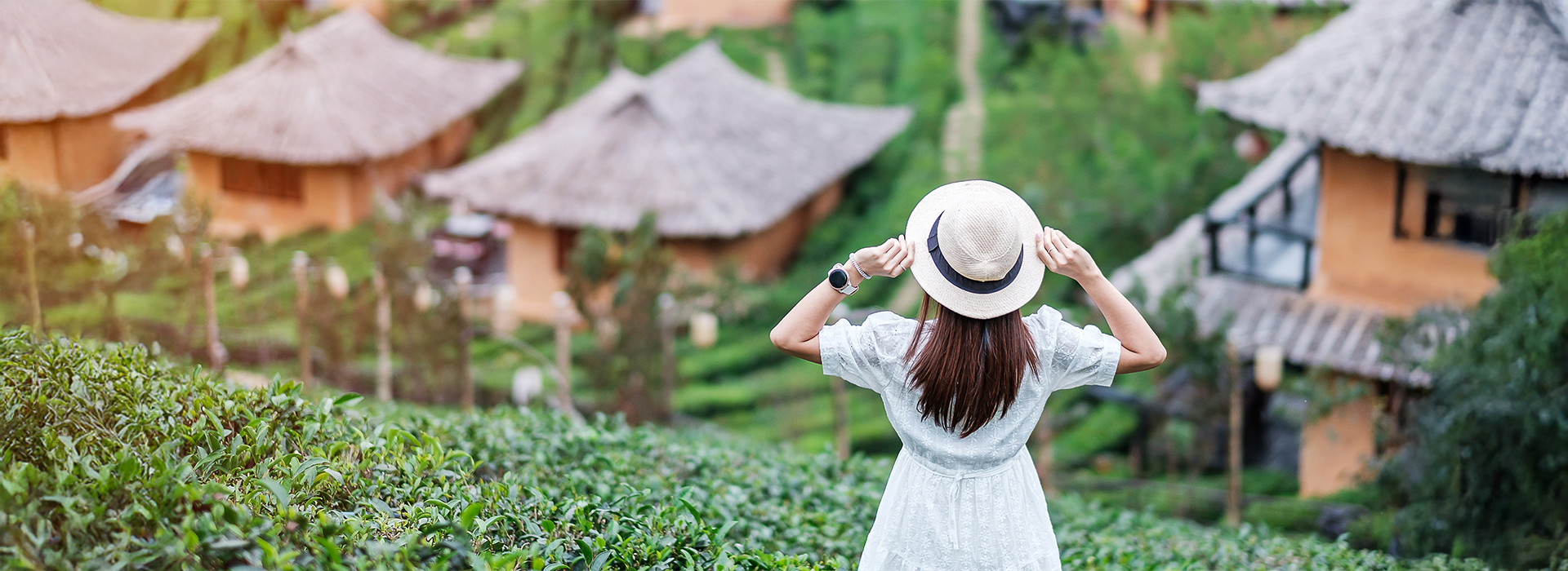 A woman enjoying a scenic eco-village surrounded by greenery and traditional houses – Sustainable Travel Tips for eco-conscious explorers.