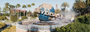 The iconic Universal Studios Orlando globe spinning near the entrance, surrounded by palm trees and mist.