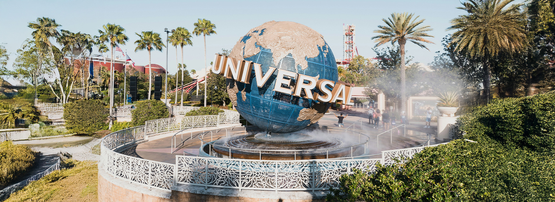 The iconic Universal Studios Orlando globe spinning near the entrance, surrounded by palm trees and mist.