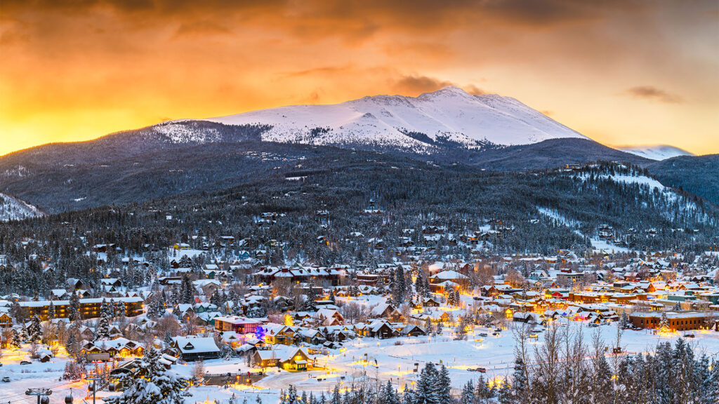 A sunset over a snow-covered Breckenridge Colorado ski town, showcasing a festive, winter atmosphere in the heart of the Rockies.