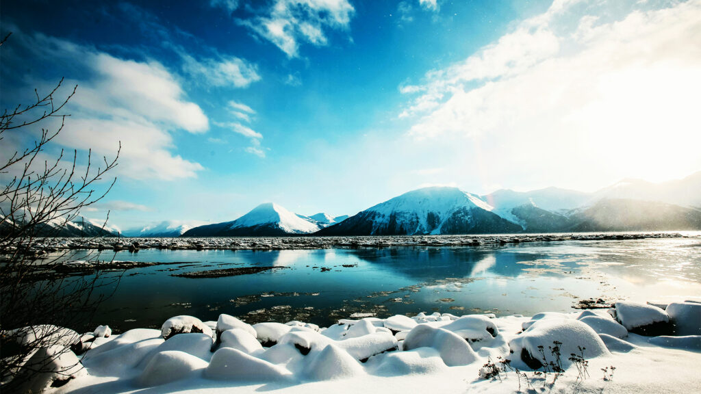 A pristine snowy landscape with mountain views in Alaska, showcasing the beauty of December.