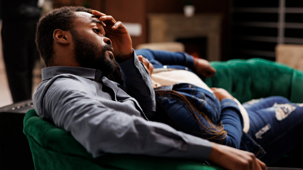 A couple lounging on a green sofa in a hotel lobby, possibly waiting to book a hotel room or enjoy their stay.