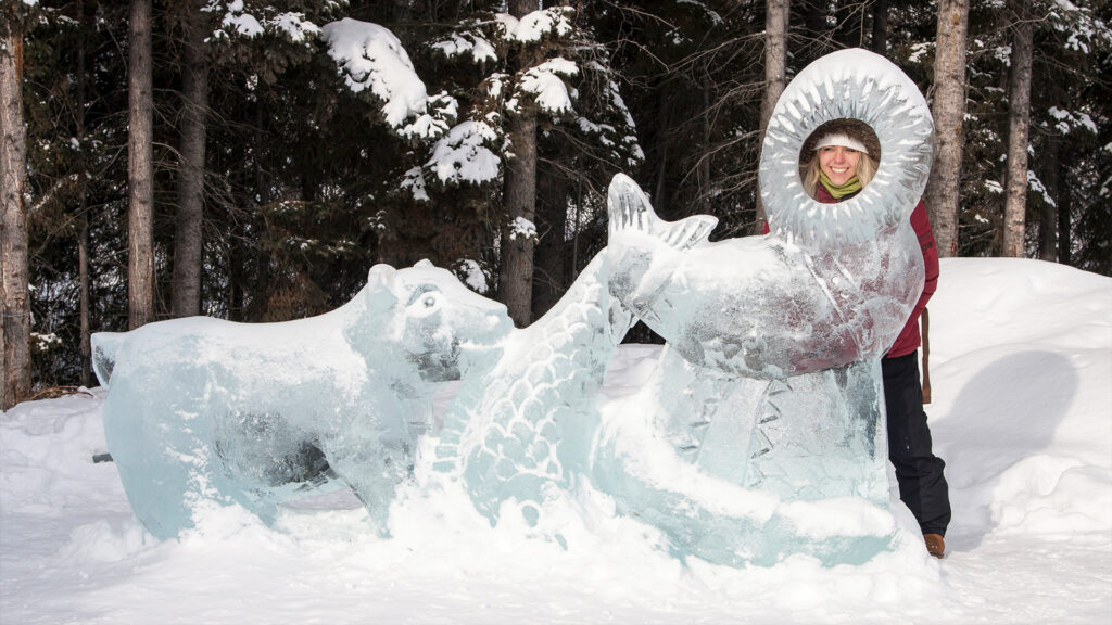 A beautifully crafted ice sculpture of a bear and fish surrounded by snow in Alaska.