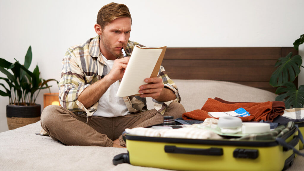 A man carefully checking his packing list while preparing for his winter trip, making sure to pack all essentials.