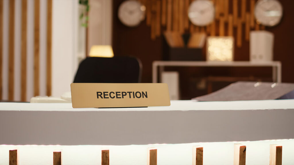 A clear view of a hotel reception desk, featuring a sign with the word "RECEPTION" for guests checking in or booking a hotel room.