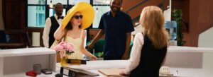A woman arriving at a hotel reception with a large sunhat, ready to check in and book a hotel stay for her vacation.