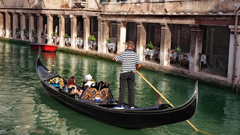 A couple enjoying a serene gondola ride through the canals of Venice, making for an unforgettable romantic getaway.