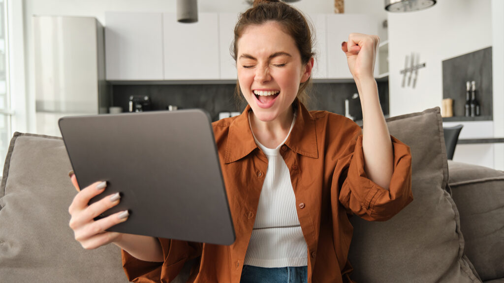 A happy woman celebrates after successfully booking a hotel room online via tablet.