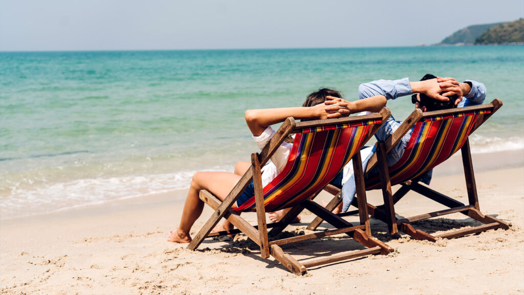 Couple relaxing on colorful deck chairs on a Florida beach, enjoying the warm February weather.