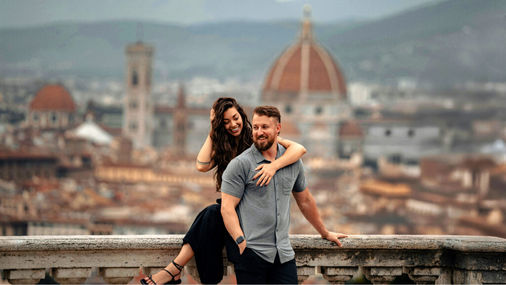 A couple smiling and posing with the city of Florence in the background, offering a charming and scenic spot for a romantic getaway.