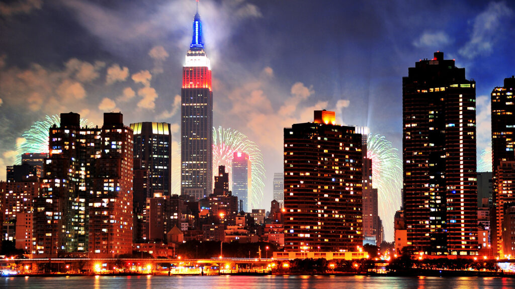 New York City skyline at night with fireworks and illuminated buildings
