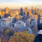 A person taking a photo of the city skyline at sunset in February, capturing the city's beauty.