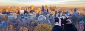 A person taking a photo of the city skyline at sunset in February, capturing the city's beauty.