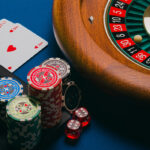 A casino table with poker cards, chips, and a roulette wheel, representing the gambling experience in Las Vegas and Macau.