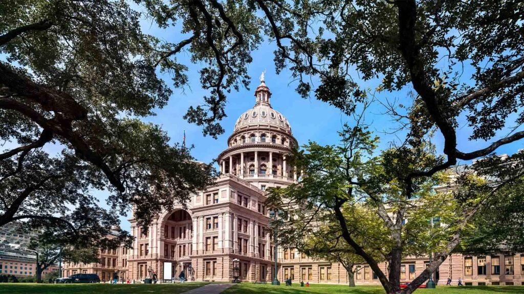 The Texas State Capitol building in Austin, framed by lush trees, showcasing its stunning architecture and grandeur.