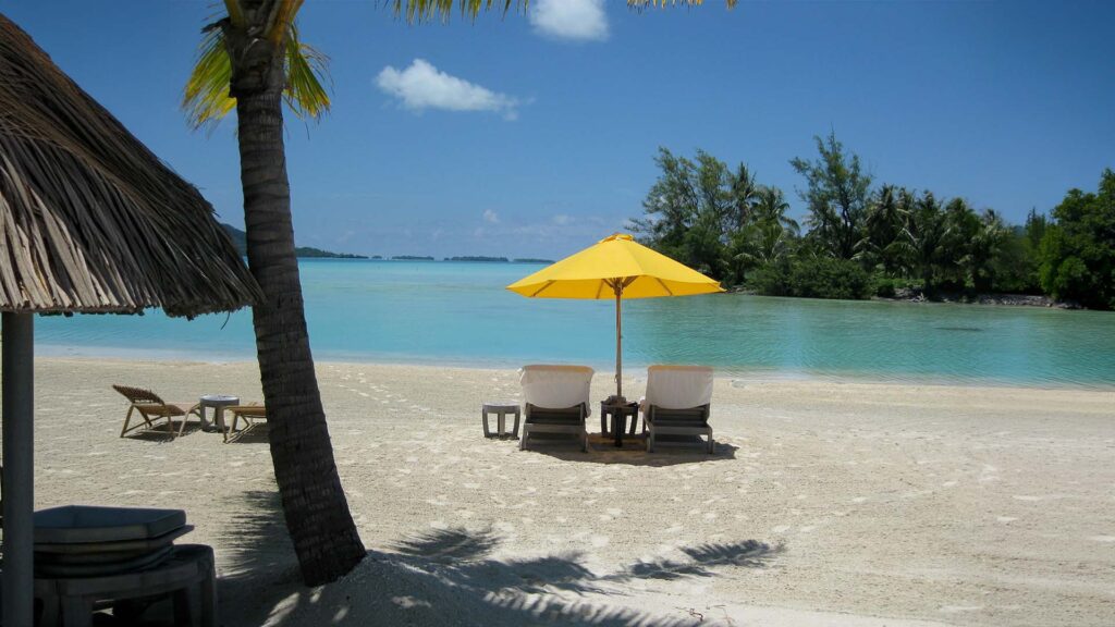 Bora Bora beach destination with a tropical beach lounge under a yellow umbrella overlooking clear blue waters