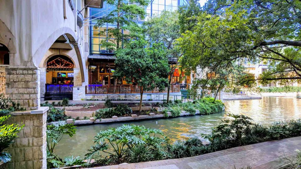 The picturesque San Antonio River Walk, lined with lush greenery and restaurants, offering a peaceful and scenic atmosphere.