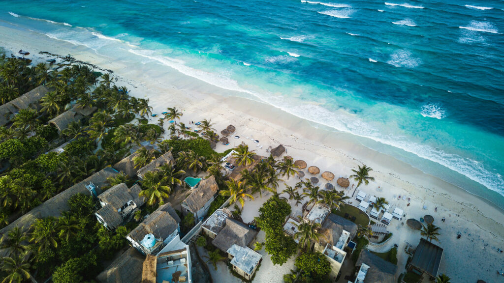 Best international beach destinations with a serene beach in Tulum, featuring palm trees and a vibrant beach umbrella