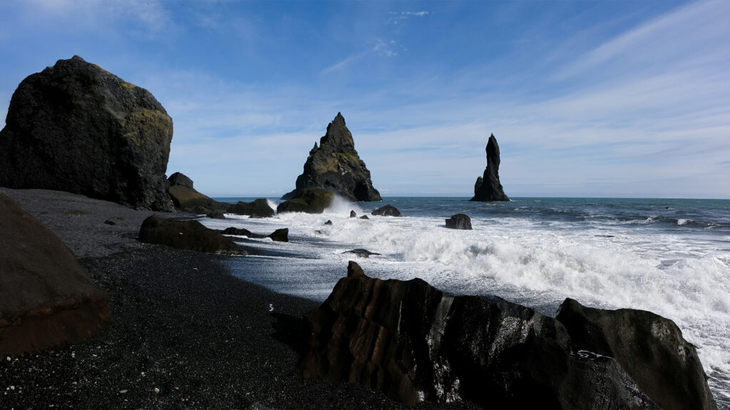 The stunning black sand beach with towering rocks and waves crashing along the shore in Iceland.