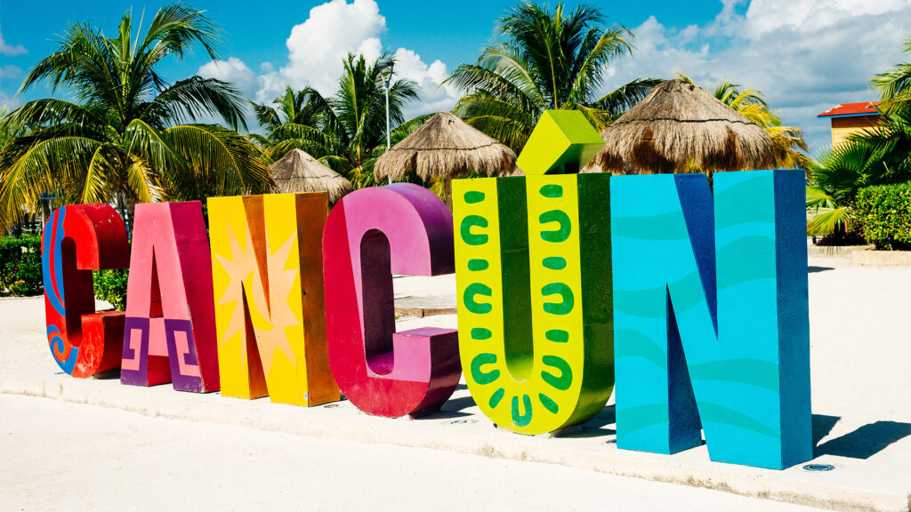 Colorful Cancun sign with tropical palm trees, perfect for your Cancun Summer Travel.